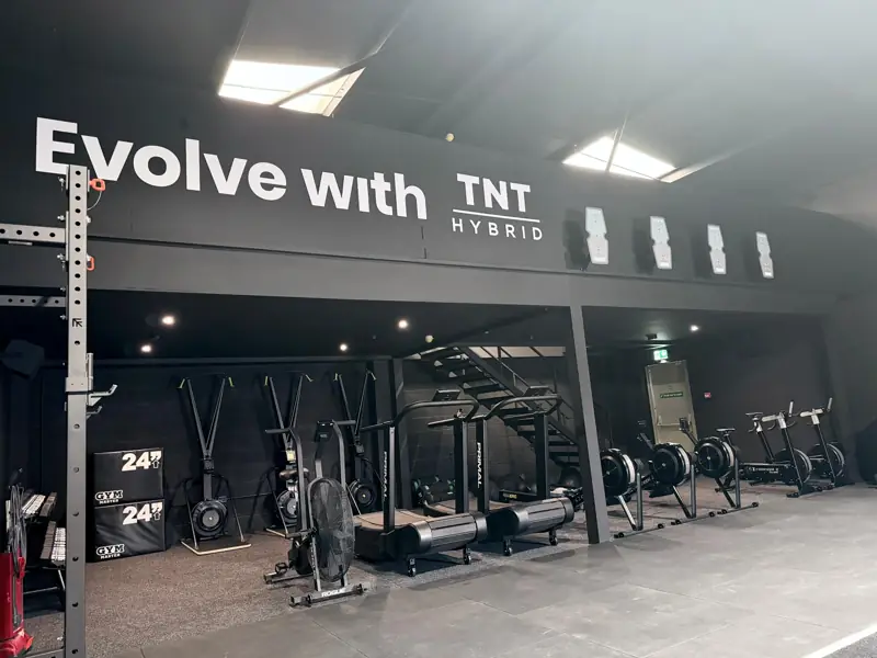 Evolve with TNT Hybrid signage above the conditioning area with assault bikes, rowers and curved treadmills