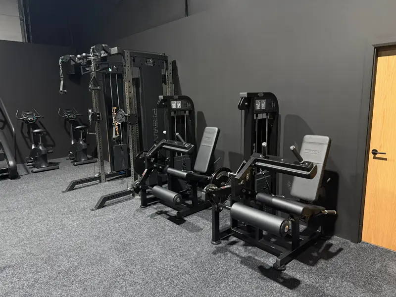 Seated leg press and leg extension machines beside upright bikes in the resistance training room